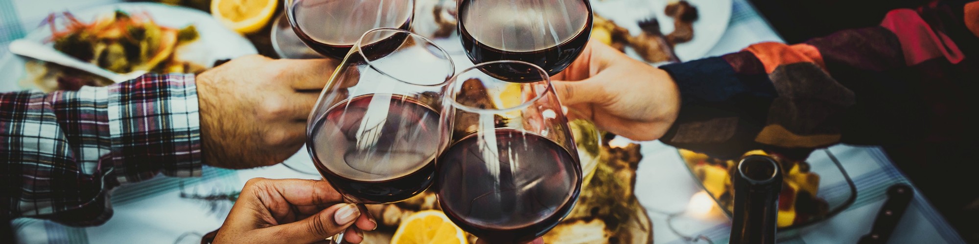Freunde stoßen beim Essen  an mit Rotwein