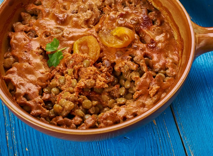 Linsen Bobotie in ofenfester Form auf blauem Holztisch